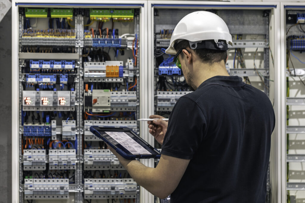 MEP engineer inspecting electrical control panel commercial building